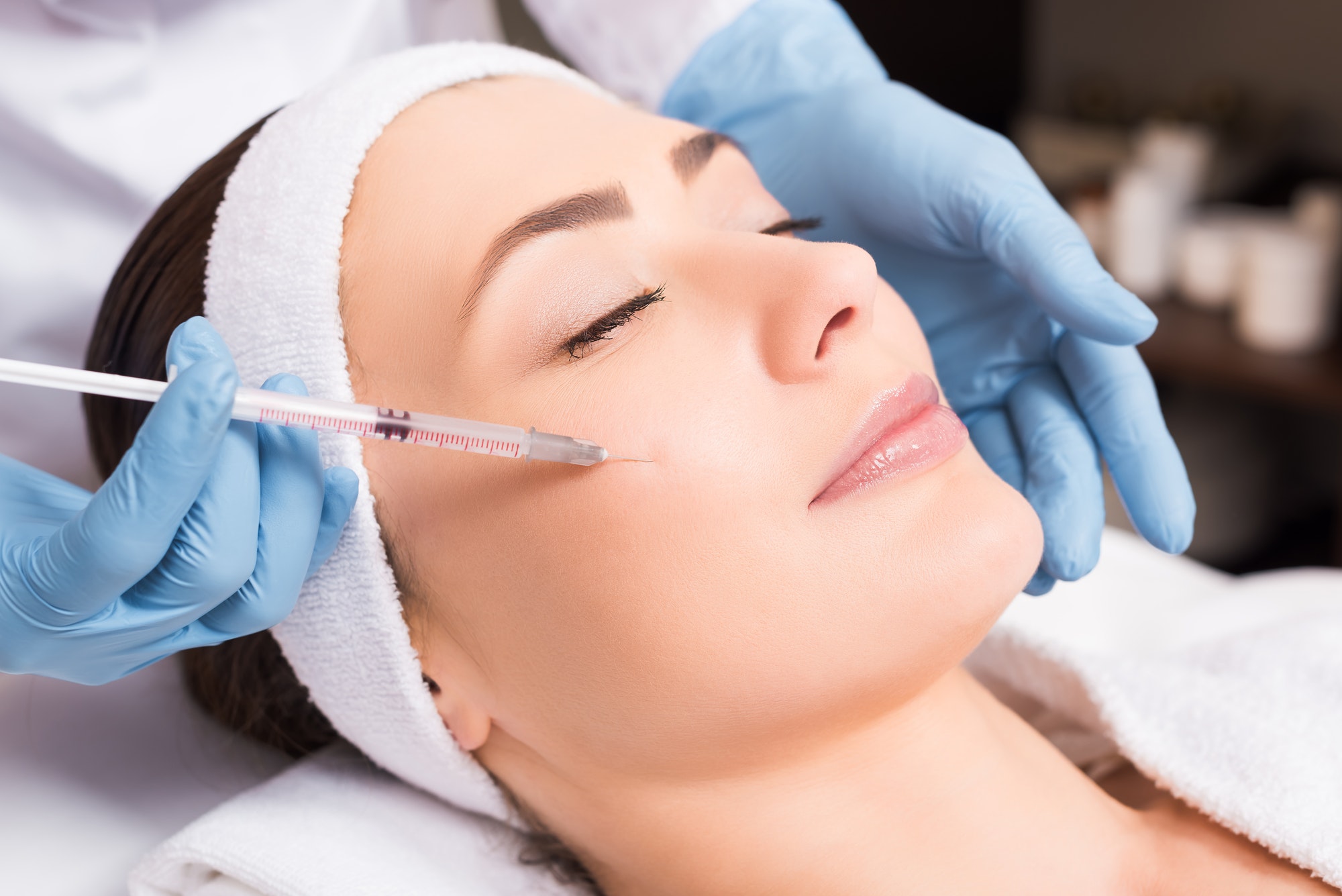 beautician making injection face attractive woman at beauty salon